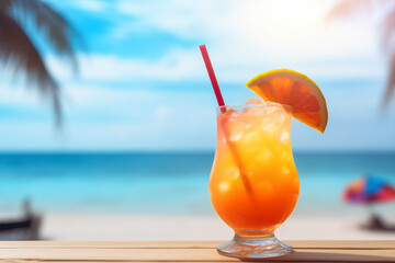 A bright summer cocktail decorated with a slice of orange stands on a table in a beach bar, a blurred background of a sandy beach with palm trees and the azure sea. Space for text