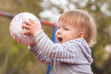 Cute little baby boy having fun playing with colorful ball in the park
