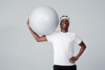 Handsome sporty black man holding large gym ball over his head