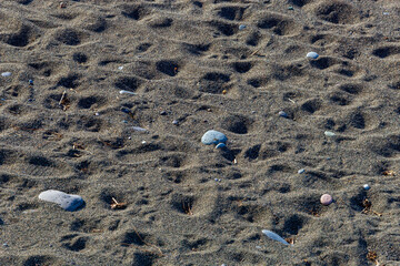 Pebbles and patterns in sand at a beach, natural abstract texture.