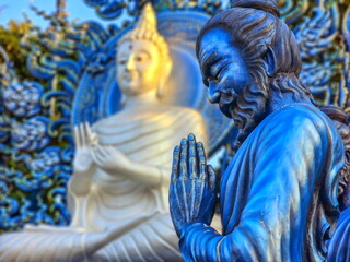 Praying monk statue at Wat Rong Suea Ten Blue temple, Chiang Rai, Thailand - obrazy, fototapety, plakaty