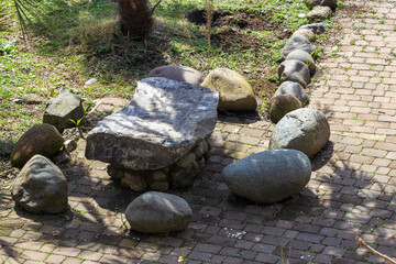Stone chairs and table alongside a cobblestone path in a serene garden