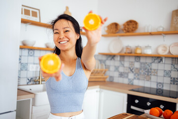 An attractive young Asian woman smiles and shows oranges to the camera. A beautiful Thai girl...