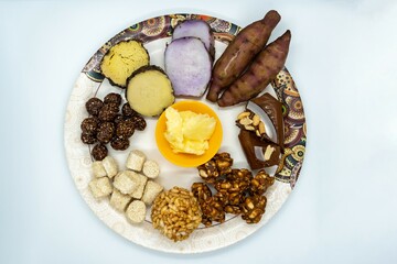 Maghe Sankranti Makar Festival Celebration Food Plate of Muri Ladoo, Sesame Ladoo, Yam, Sweet Potato, Jaggery, Peanuts Ladoo Ghee in India and Nepal