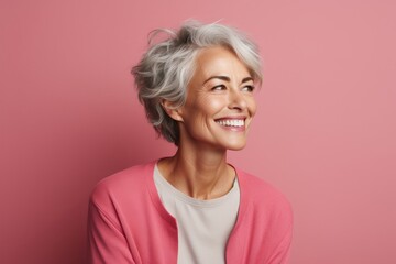 Portrait of happy senior woman with short grey hair on pink background