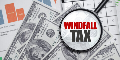 WINDFALL TAX word on magnifying glass with dollars and charts