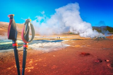Geothermal active zone Hverir near Myvatn lake and hiking poles in Iceland, resembling Martian red planet landscape, at summer and blue sky. - obrazy, fototapety, plakaty