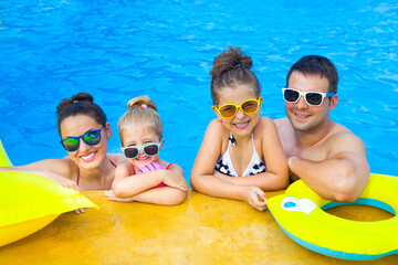 Happy family with two kids having fun in the swimming pool