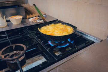 A restaurant kitchen with a frying pan where potatoes are fried