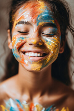 Close-up of a young girl smiling with her face covered in colorful paint, exuding happiness and creativity.