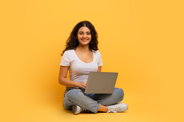 Happy young hindu lady typing on laptop keyboard