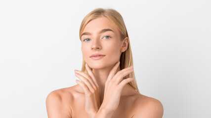 blonde lady posing holding hands near face over white backdrop