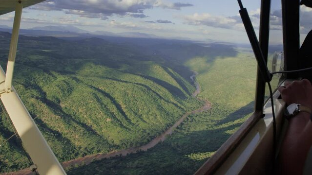 Ariel of a river flowing through valleys within the savannah from a light aircraft during the afternoon in Kenya.