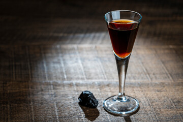 Homemade dark damson plum brandy in glasses on a wooden table, closeup. Drink from dry plums