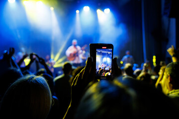 Fototapeta na wymiar Group of People Enjoying a Live Concert with Stage Lights and Mobile Phones