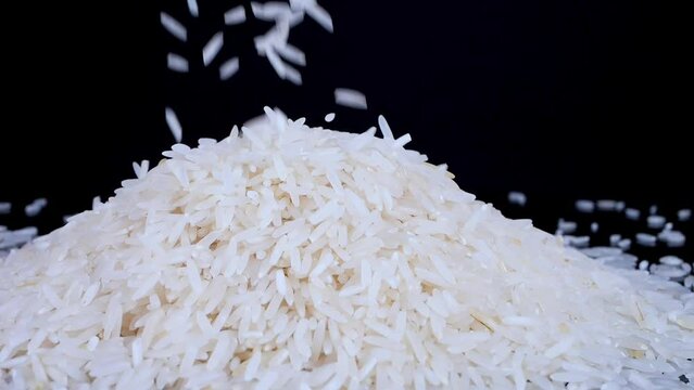 Basmati white rice falling in slow motion on a black spinning background. Basmati rice is a fragrant, delicious long-grain white rice. Healthy food concept.