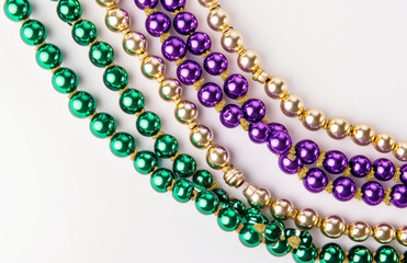 Mardi gras beads on a white background, uniformly staged, purple, green and beige