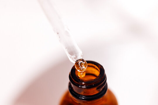 Close up of brown serum or oil glass with mock up on bottle on mirror background