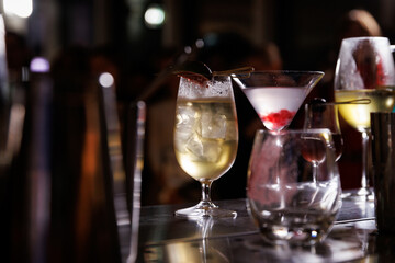 Collection of colorful cocktails on a bar counter with a blurred background of people enjoying their drinks.