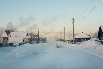 Winter village of Cherdyn. Winter road through a snow-covered village, severe frost, snow haze.