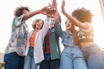 Group of students celebrating by joining their hands the successes of their university grades