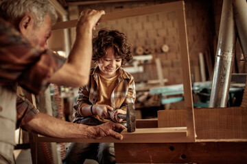 Senior man teaching grandson woodworking in workshop