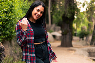 beautiful Latin woman inviting you to enjoy the place. with a very happy expression, smiling and very expressive, in an outdoor park