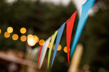 Festive party venue decorated with colorful pennant banners and string lights - obrazy, fototapety, plakaty