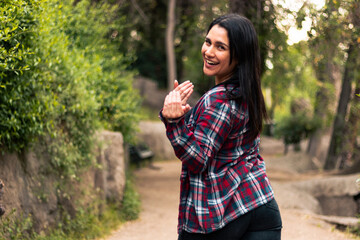 beautiful Latin woman inviting you to enjoy the place. with a very happy expression, smiling and very expressive, in an outdoor park