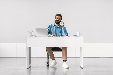 Relaxed businessman on a phone call at workdesk