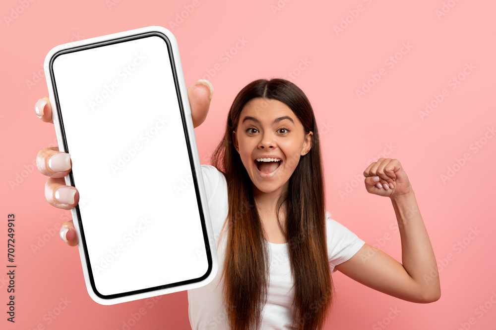 Wall mural overjoyed teen girl celebrating success, showing big phone