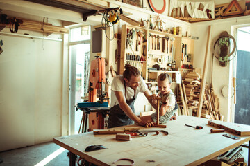 Father and daughter enjoying carpentry work together in a sunny workshop
