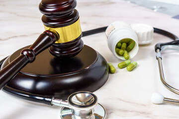 Wooden judge's hammer next to a pack of pills and a stethoscope on a table. Right to ensure access to medical care.