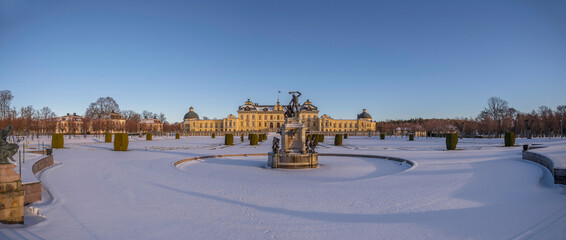 Panorama, snowy view over a winter garden and a castle in a park, on the Drottningholm island in...