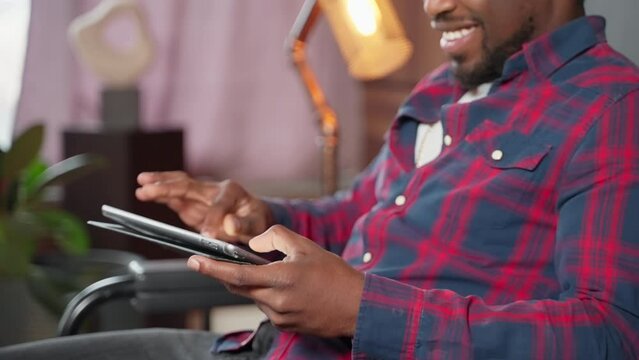 Happy smiling african american guy typing message on tablet in social media.