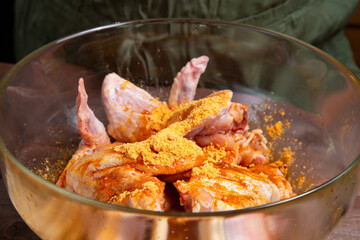 Soy sauce is poured into a glass plate with chicken wings with golden spices