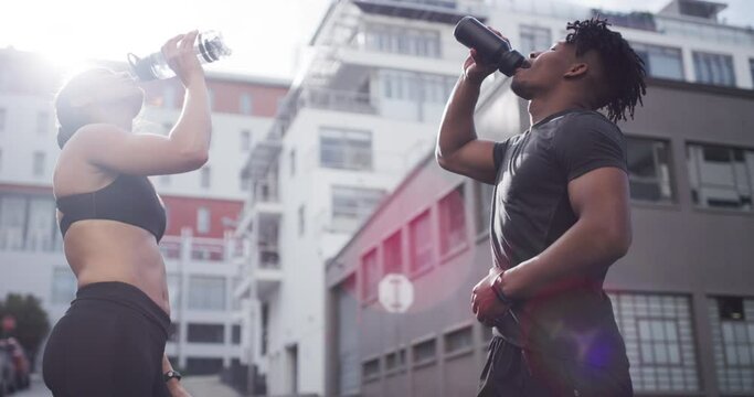 Couple, drinking water and fitness in city for hydration, health body and relax together by outdoor workout. Man, woman and diversity in thirst with natural glow, wellness and post exercise in summer