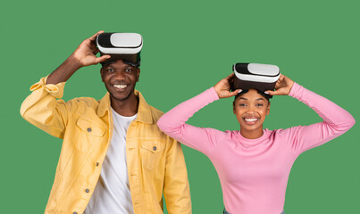 Black man and woman put VR glasses on, green background
