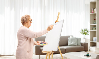 Elderly woman painting on a canvas