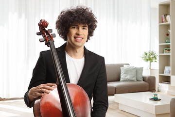 Portrait of a young male artist with a cello posing at home