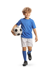 Full length portrait of a boy in a football kit walking and carrying a ball