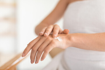 Closeup of woman's hands apply moisturizer cream in modern bathroom - obrazy, fototapety, plakaty