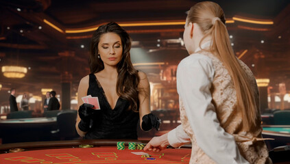 Attractive woman in black dress at poker table for blackjack game in casino. Woman with cards in...