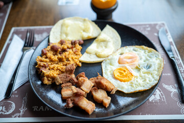 delicious colombian breakfast platter with pork cracklings rice and beans corn cake with cheese and two fried eggs