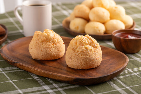 Brazilian cheese breads on wooden cutting board. Breakfast table. Black coffee.