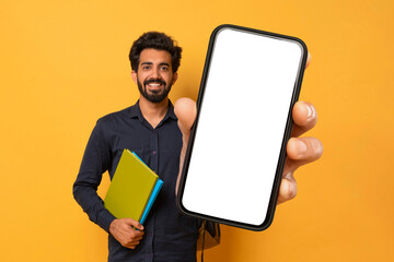 Smiling Indian Guy Posing With Workbooks, Showing Smartphone