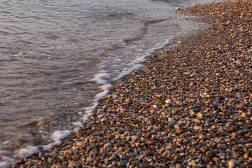 Obraz premium The waves of the sea wash the shore of the pebble beach..​
