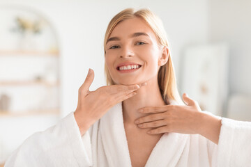 woman touching her flawless soft skin on neck in bathroom
