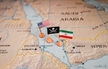 Flags of the USA and Iran surrounding a pirate insignia onto a map of the Red Sea region. It...