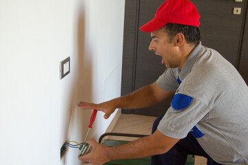 Image of an electrician as he installs an electrical plug and gets an electric shock. Job security
